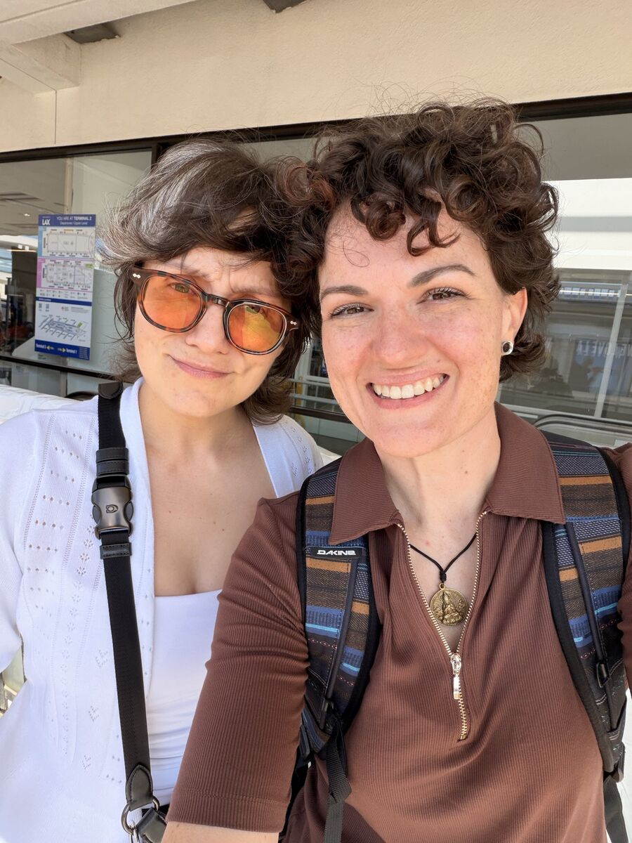 Heidi Briones and her wife, Jena, smiling together in a selfie at the airport